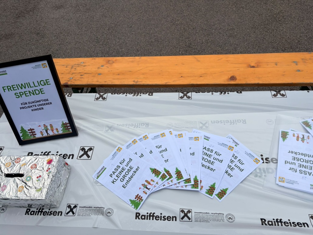 Tisch und Bank mit Entdeckerpass und einer Dose für Freiwillige Spenden